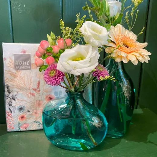 Håndbundet buket med lisianthus og gerbera i en grøn glasvase